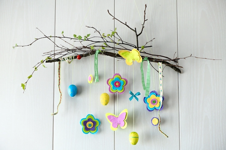 wanddeko aus zweigen, filzblumen und bunten eiern