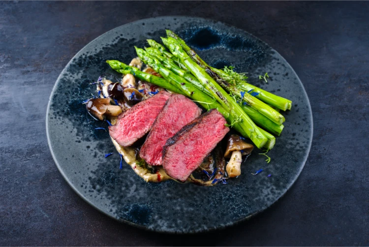 angus rindsteak mit grünem spargel und pilzen in trüffelmousse