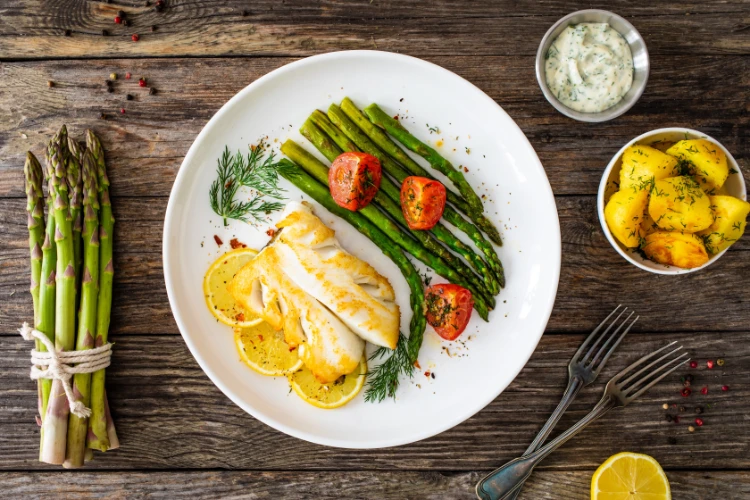 brauner heilbutt mit gekochtem grünem spargel und tomaten