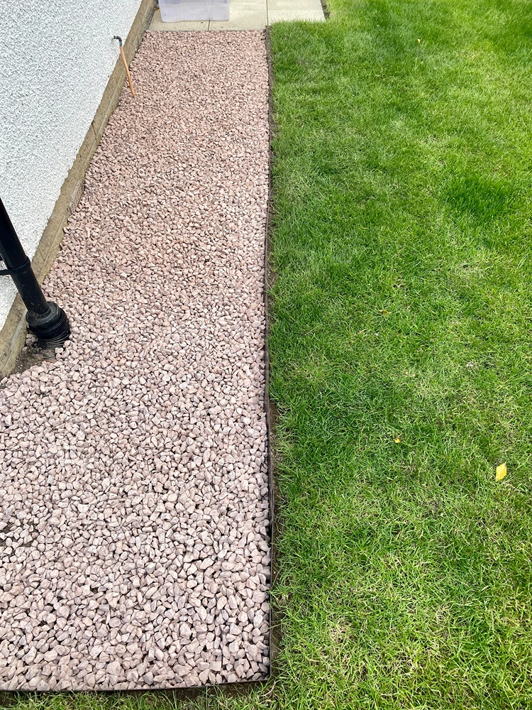 dezente metall rasenkante zwischen rasen und kiesstreifen entlang der hauswand