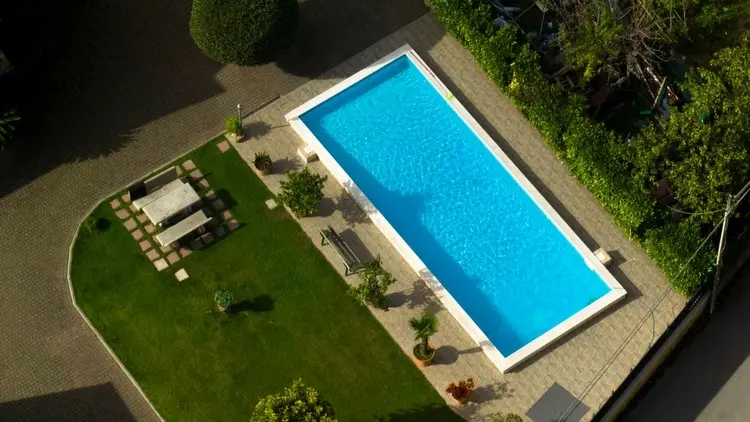 Gestaltung rund um den Pool mit schlichtem Rasen und Kübelpflanzen