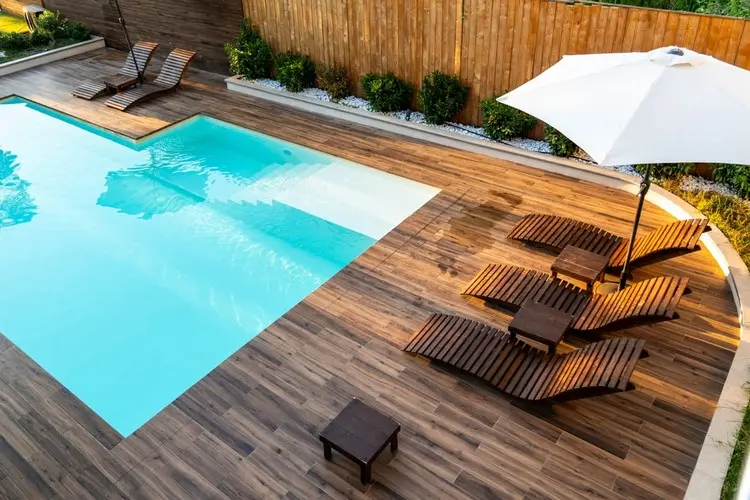 Holzdeck und schmale Kiesbeete mit Sträuchern für die Poolumrandung