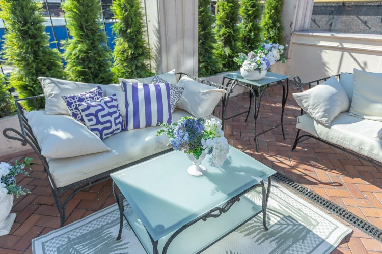 moderner balkon mit möbeln und dekorationen und sträuchern als sichtschutz