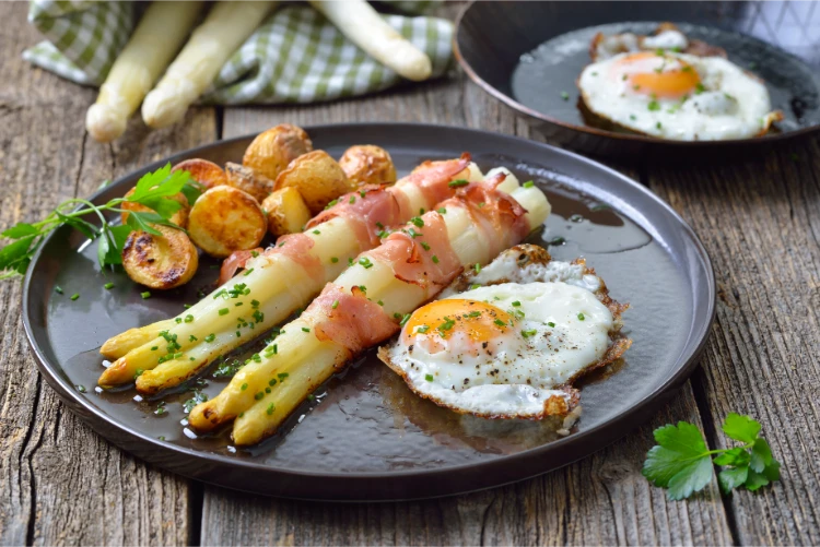 weißer spargel, gebacken in bacon streifen, mit knusprigen kartoffeln und frittierten eiern