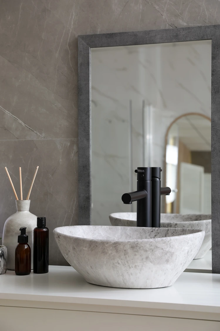 elegantes bad mit naturstein waschbecken und dunkler armatur