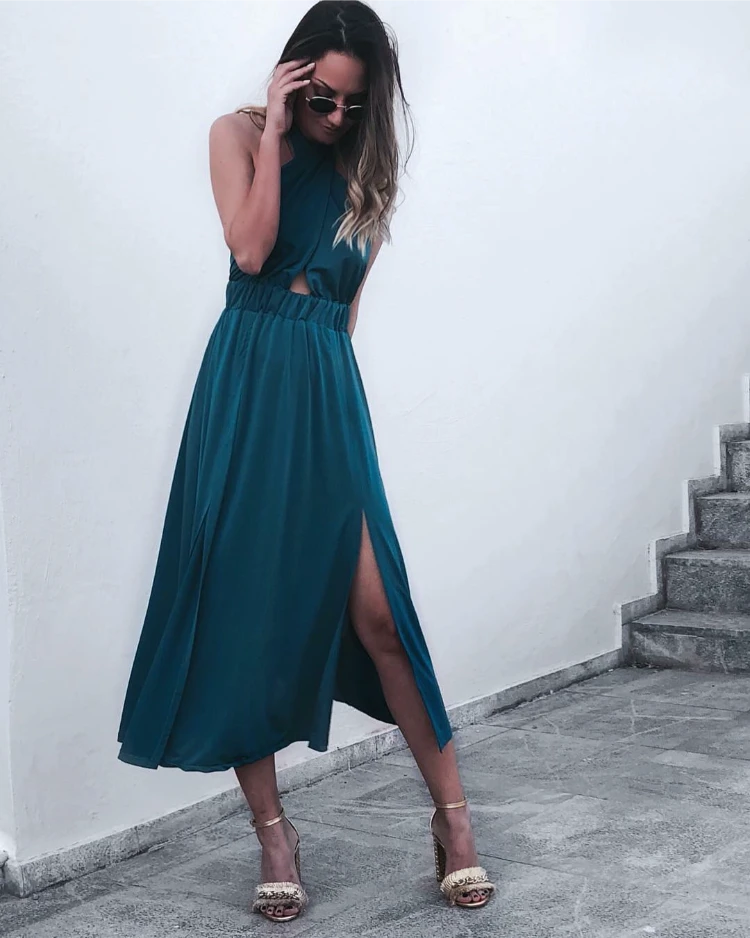 frau mit modischem petrolfarbenem kleid und goldenen sandalen