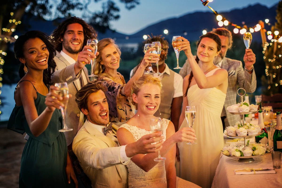 hochzeitsgäste, die während der boho hochzeit im garten champagner trinken