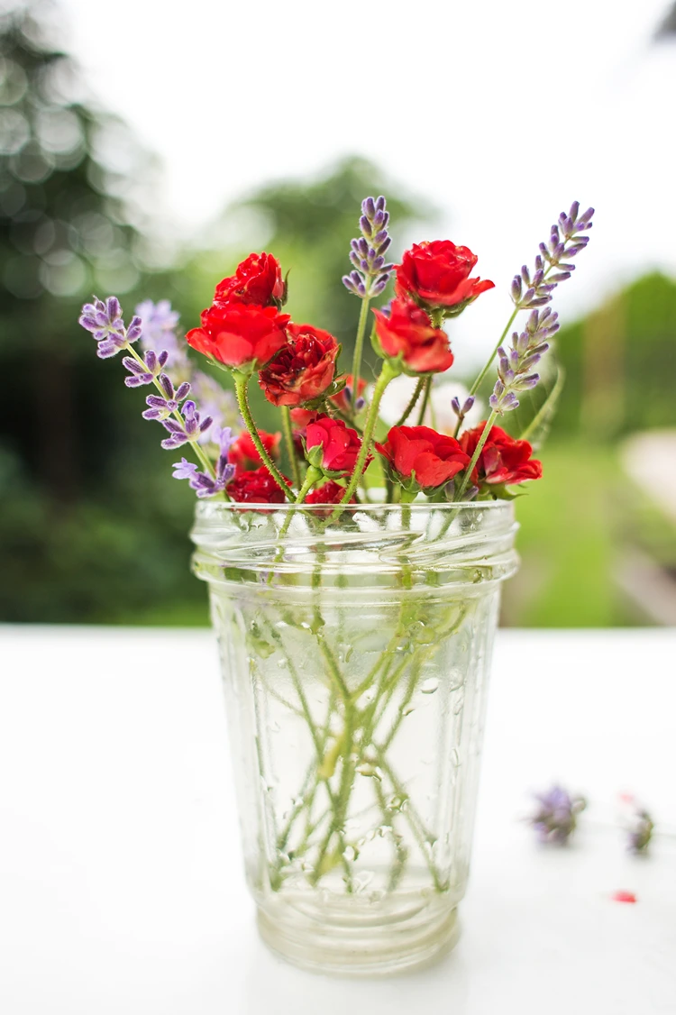 tischdeko in einem schlichten glas mini rosen lavendel