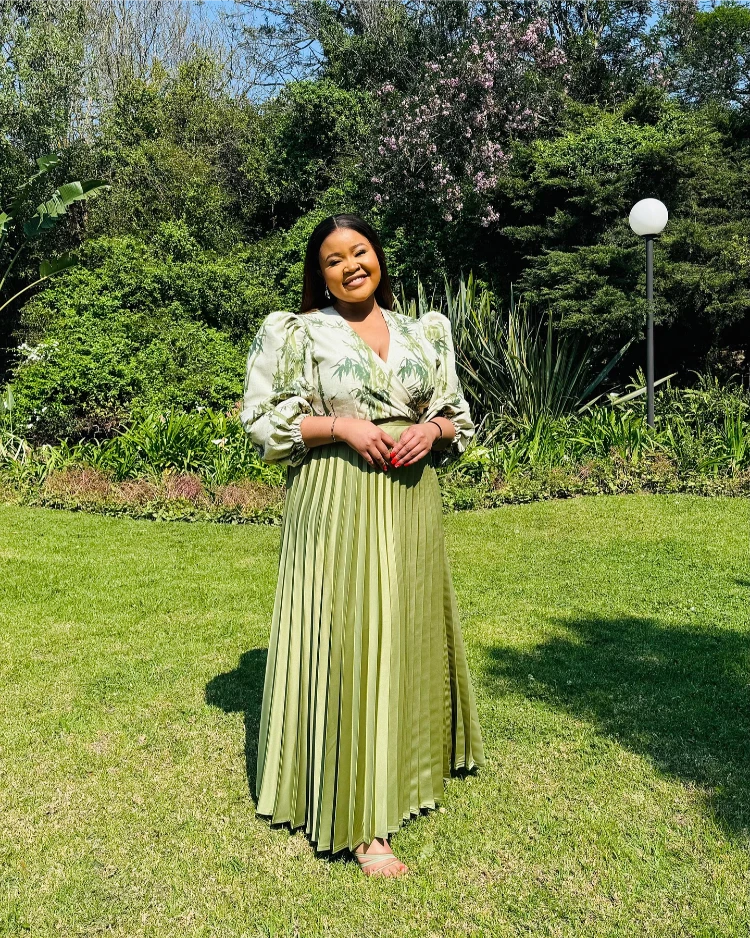 frau mit elegantem outfit in grün mit faltenrock und floraler bluse