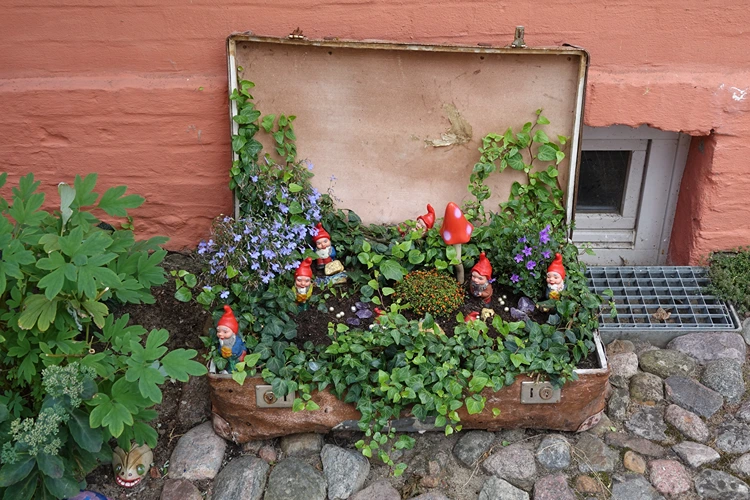 koffergarten mit deko figuren pilze und zwerge zwischen efeu