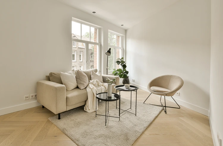 lichtdurchflutetes wohnzimmer mit beigen sesseln und modernen schwarzen couchtischen