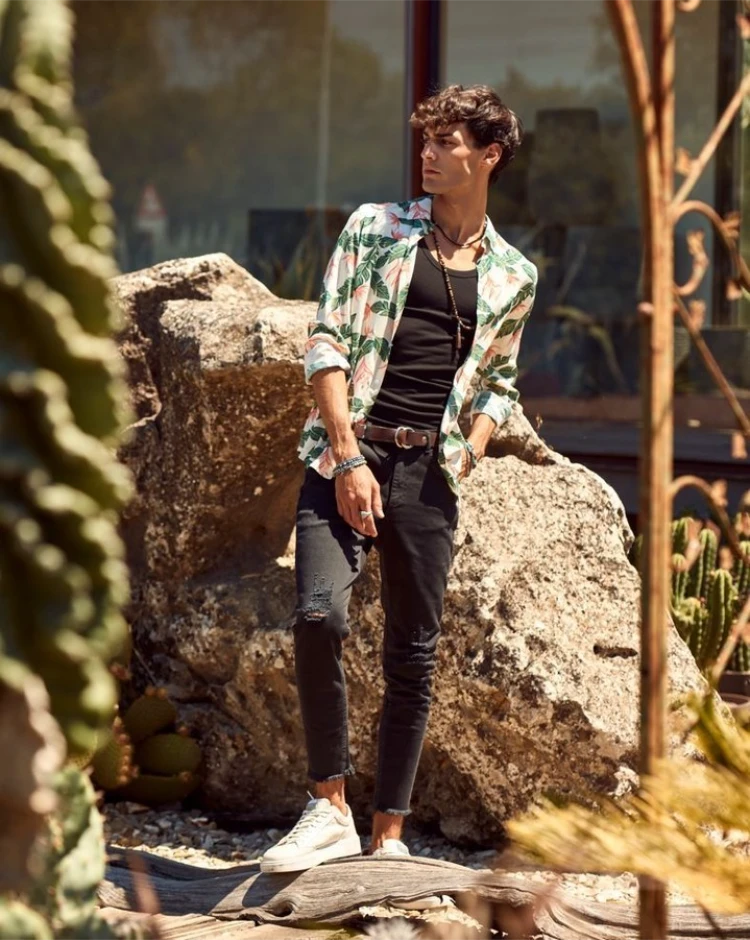 mann mit blumenhemd, schwarzem top und schwarzer jeans