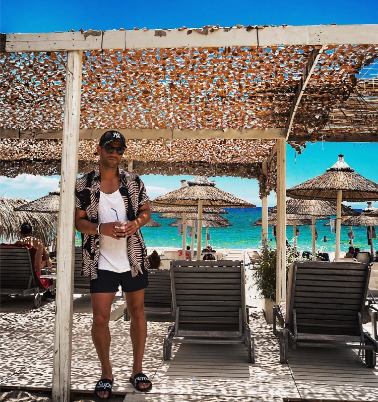 mann mit blumenhemd, weißem top und schwarzen shorts am strand