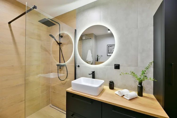Modernes Badezimmer mit rundem Spiegel als Akzent