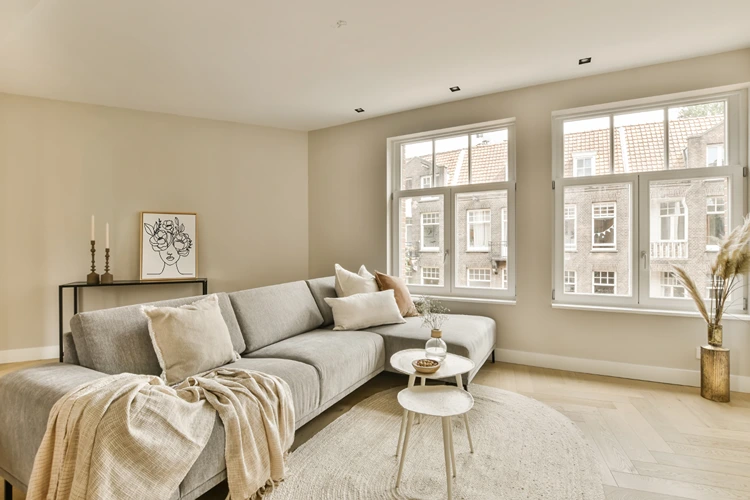 offenes wohnzimmer mit grauem ecksofa, hellen beige tönen und gemütlicher atmosphäre