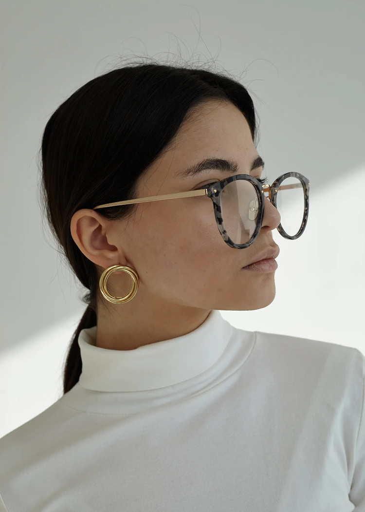 runde acetatfassung mit dezentem muster – minimalistischer look mit goldenen statement ohrringen