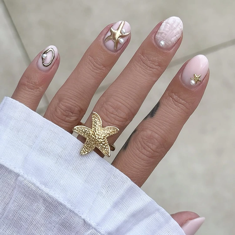 sommer nageldesign mit goldenen seesternen auf nude basis