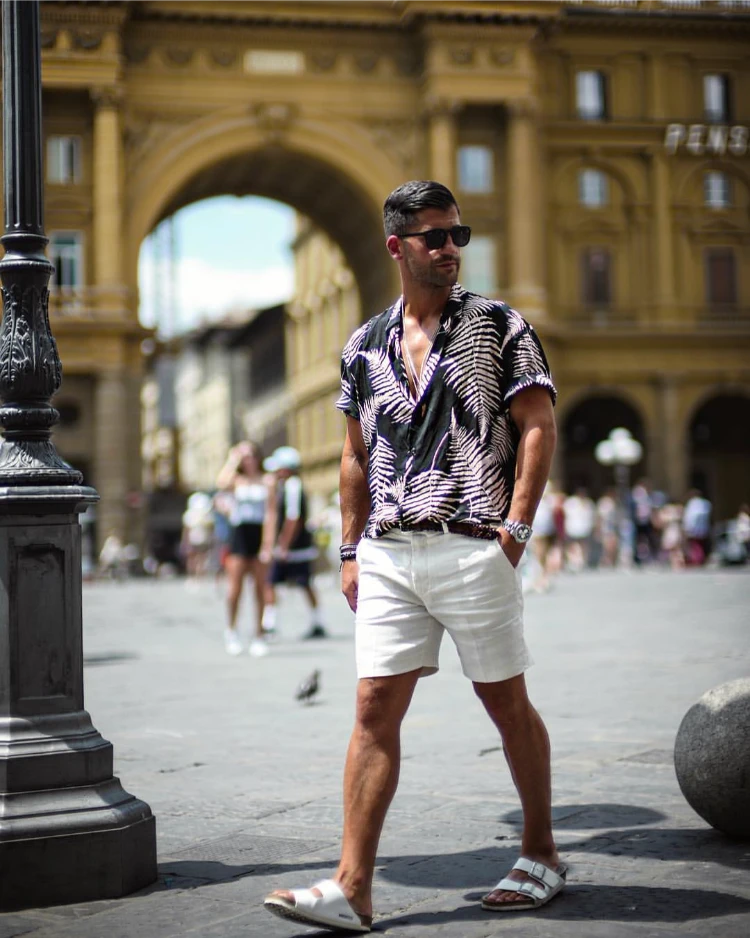 stilvoller mann mit geblümtem hemd, weißen shorts und sandalen