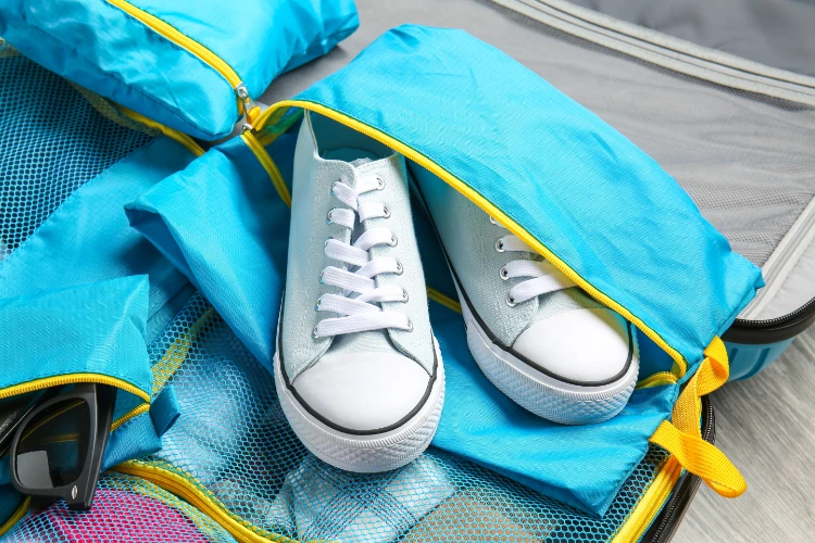 verpackung von weißen sneakers in blauem organizer im koffer