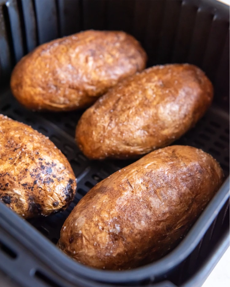 vier ganze kartoffeln, bereit zum backen in der heißluftfritteuse