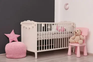 Dunkelgraue Wand mit Blassrosa in einem hellen Babyzimmer