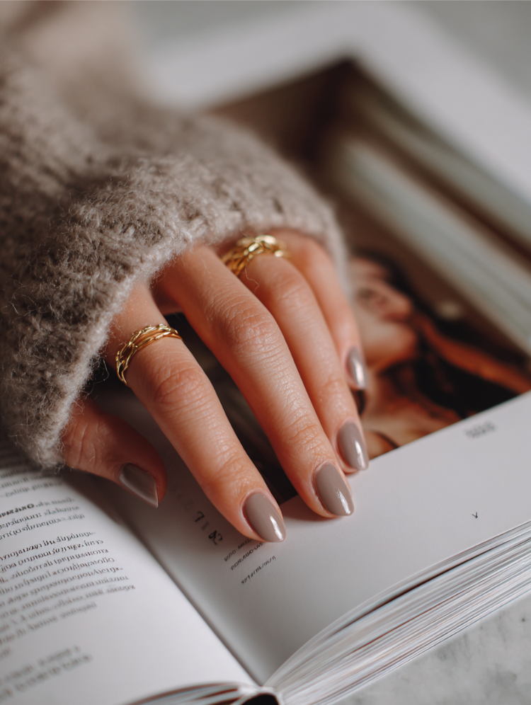 frau mit greige nägeln und goldenen ringen