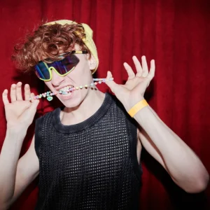 junger stylischer mann in funky kleidung, der vor der kamera im nachtclub steht