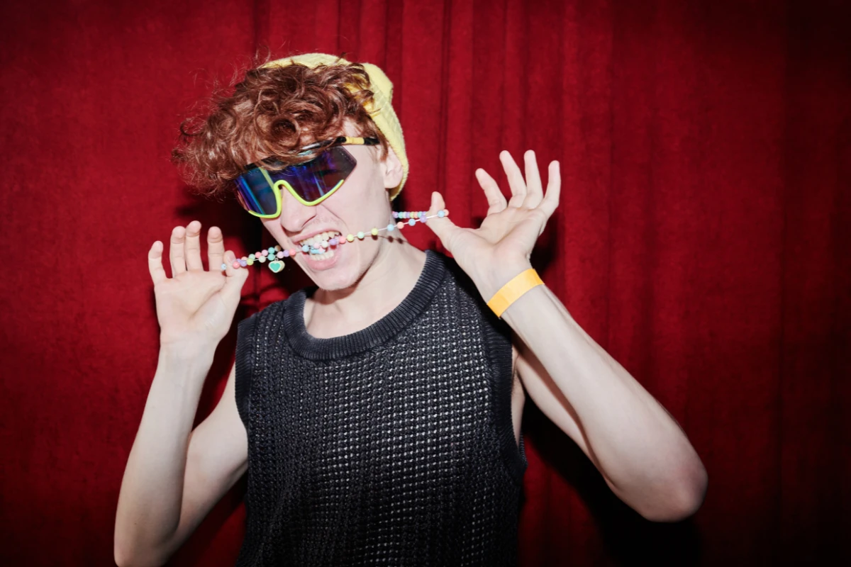 junger stylischer mann in funky kleidung, der vor der kamera im nachtclub steht