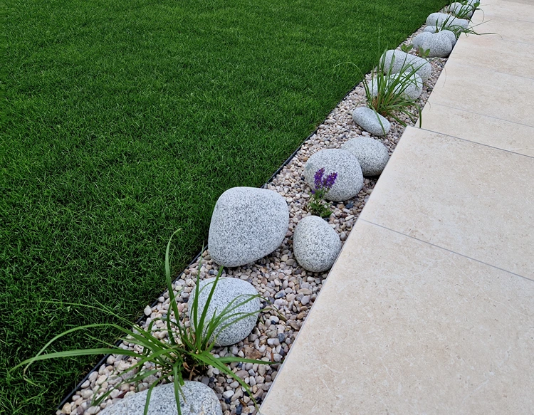 kiesstreifen mit flusssteinen und gräsern – stilvolle abgrenzung zwischen rasen und terrasse