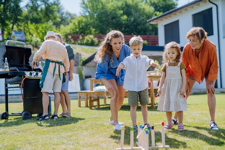 kinder und erwachsene spielen ringwurfspiel im garten grillparty