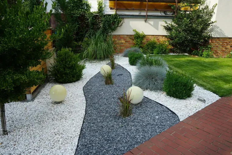 modernes gartenbeet mit weißem und grauem zierkies gestalten – ideen mit kugelleuchten und gräsern