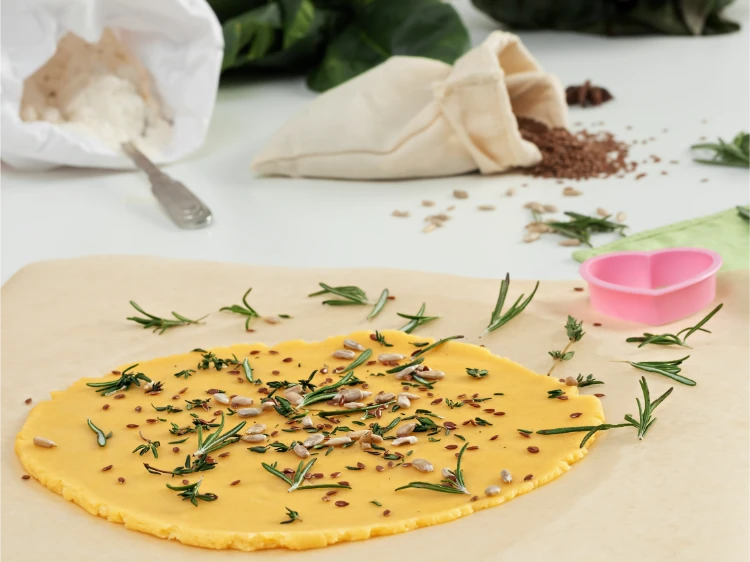 nahaufnahme von keksteig mit aromatischen kräutern, samen und parmesan auf einem tisch