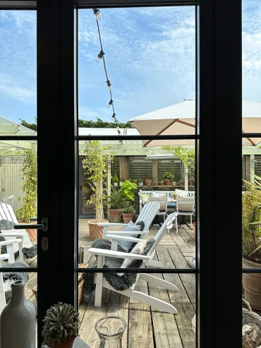 sonnenplatz mit weißen adirondack stühlen und pflanzenvielfalt