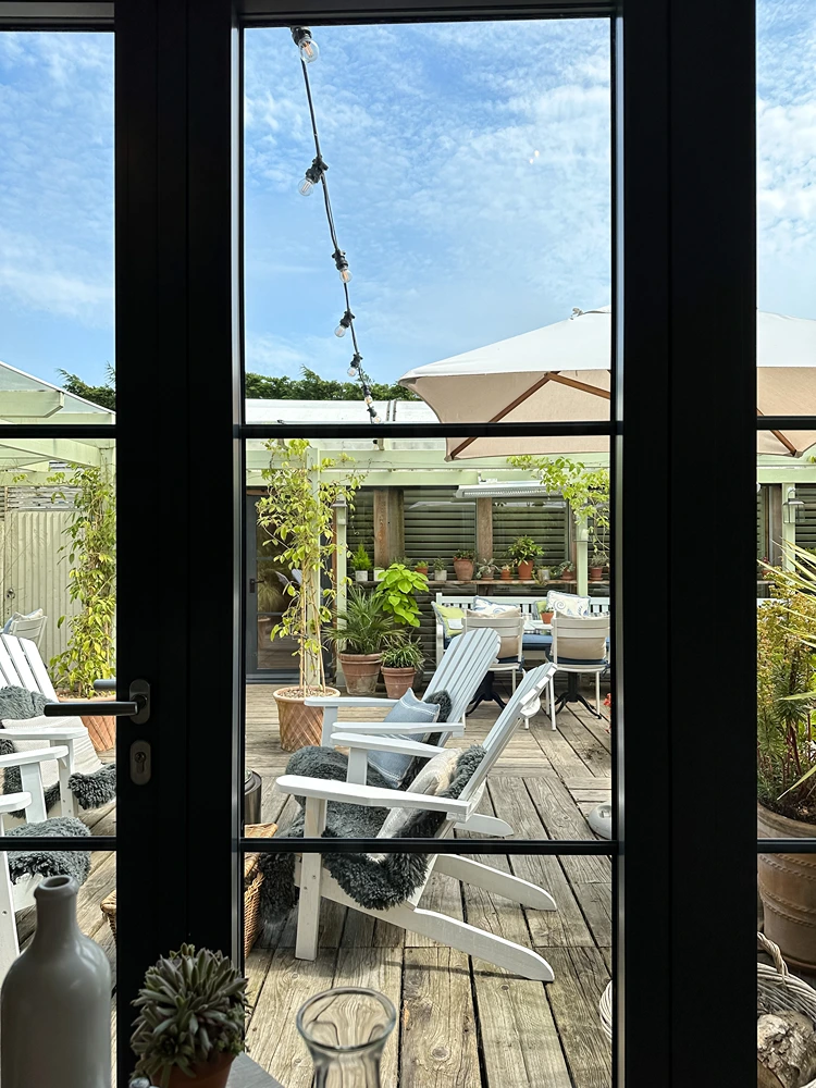 sonnenplatz mit weißen adirondack stühlen und pflanzenvielfalt