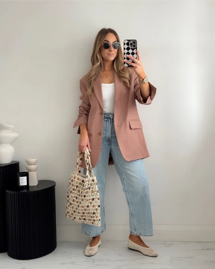 zierliche frau mit wide leg cropped jeans und rosa blazer