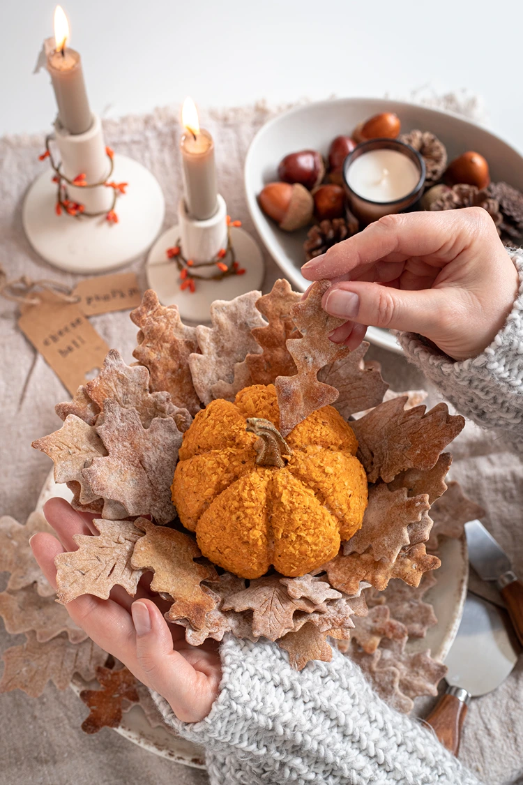 cheeseball in kürbisform mit knusprigen crackern serviert
