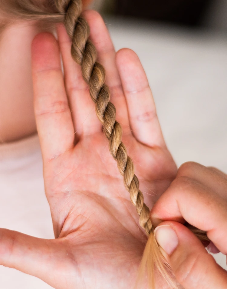 detailaufnahme kordelzopf – strähne wird festgedreht und gekreuzt