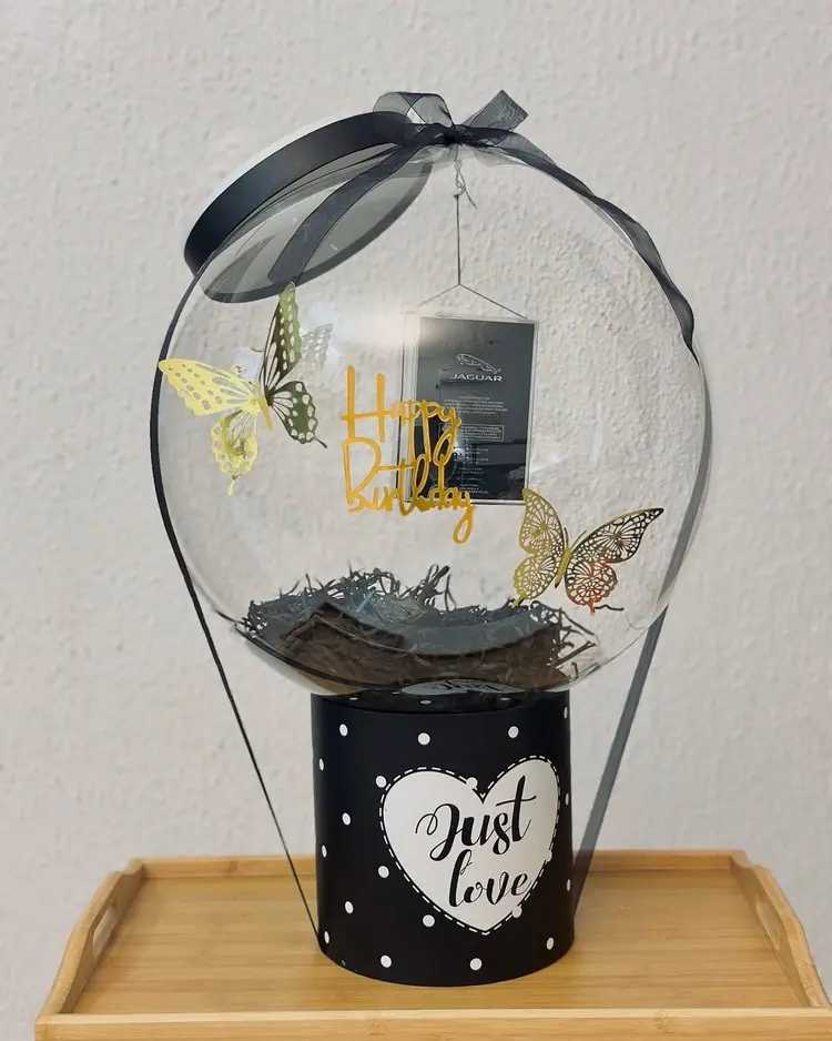 Einen Gutschein hängend an der Öffnung des Plastikballons befestigen