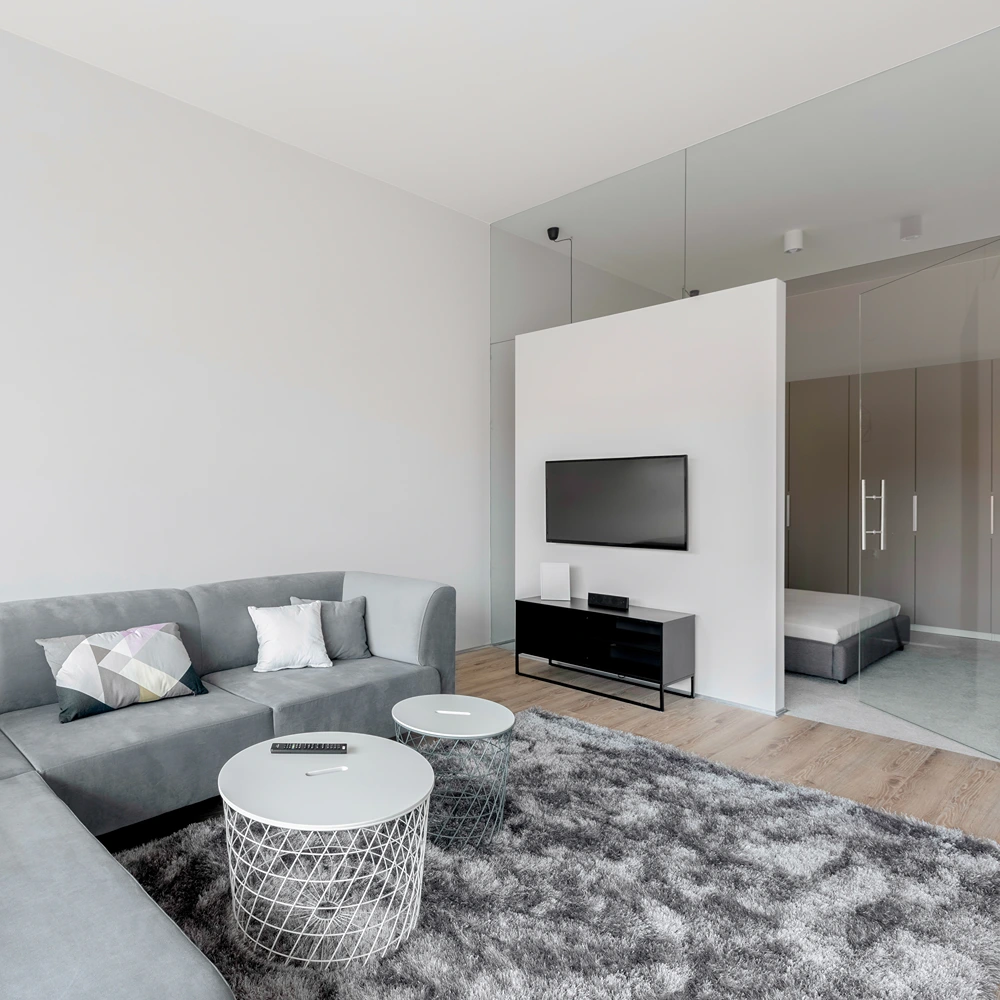 graues sofa im wohnzimmer mit blick auf glaswand zum schlafzimmer