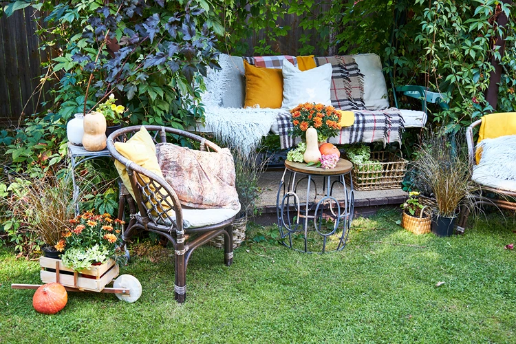 herbstlich dekorierte gartenlounge mit rattanmöbeln und laternen