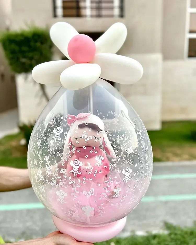 Idee für das Geschenk zum Kindergeburtstag mit Puppe im Inneren und kleinen Ballons als Deko