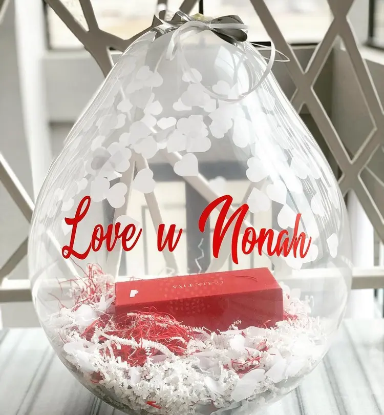 Latexballon mit Schriftzug und Geschenk in einer Schachtel