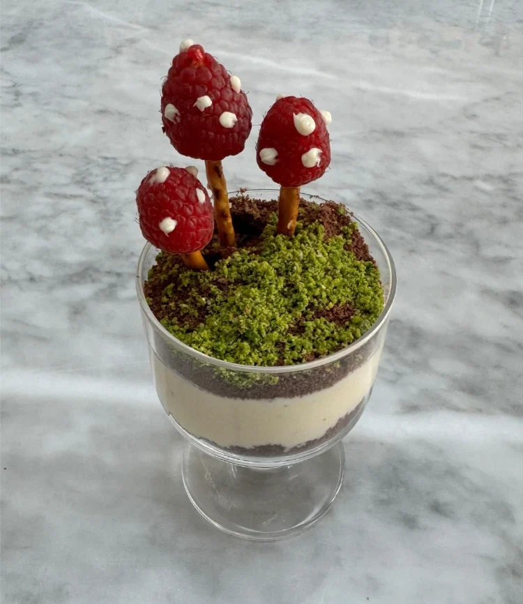 mehrschichtiges dessert im becher mit chocolate soil, der wie ein kleiner garten gestaltet ist