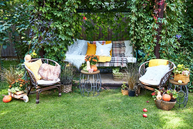 pergola sitzecke mit kissen, decken und herbstdeko