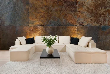 Steinwand mit großen Platten in Rostoptik, von unten beleuchtet