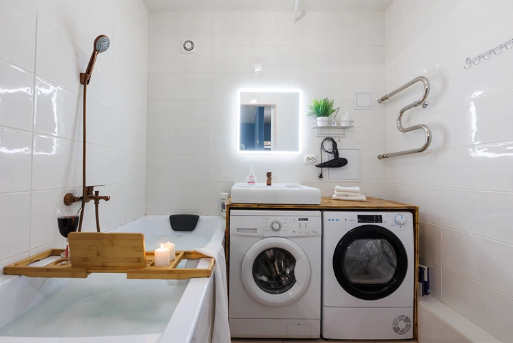 Trockner und Waschmaschine neben der Badewanne aufstellen und mit Waschtischplatte schmücken