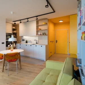 wohnküche mit gelbem flur und transparenten stühlen