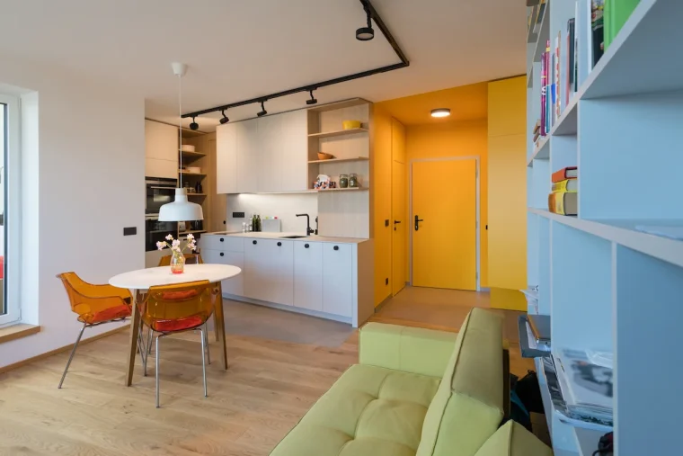 wohnküche mit gelbem flur und transparenten stühlen