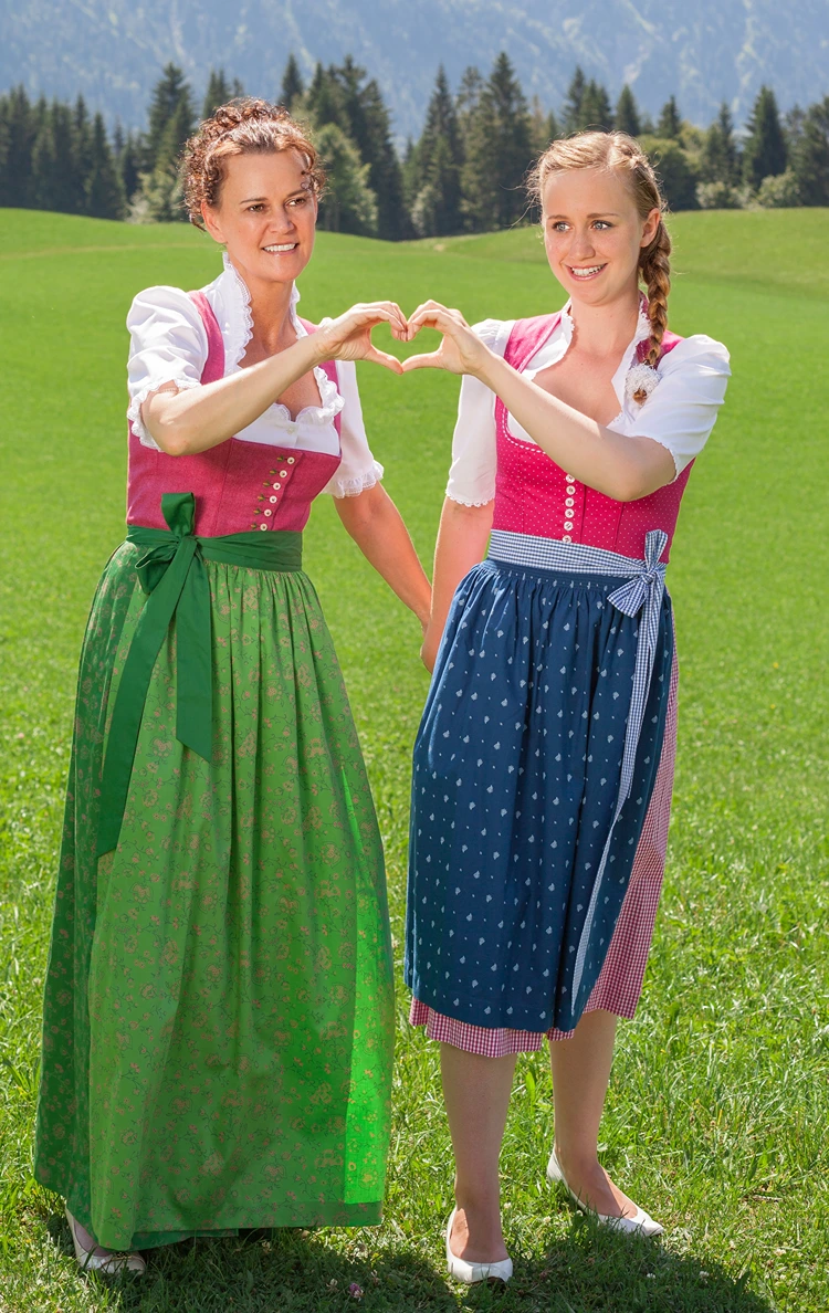 zwei frauen im dirndl mit traditionellen frisuren auf der wiese