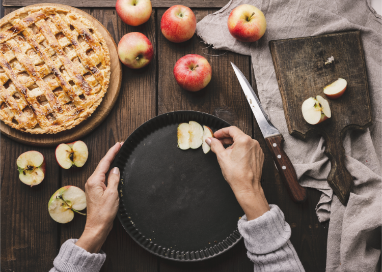 eine frau legt apfelscheiben auf ein rundes backblech, um apfelkuchen in der heißluftfritteuse zu backen